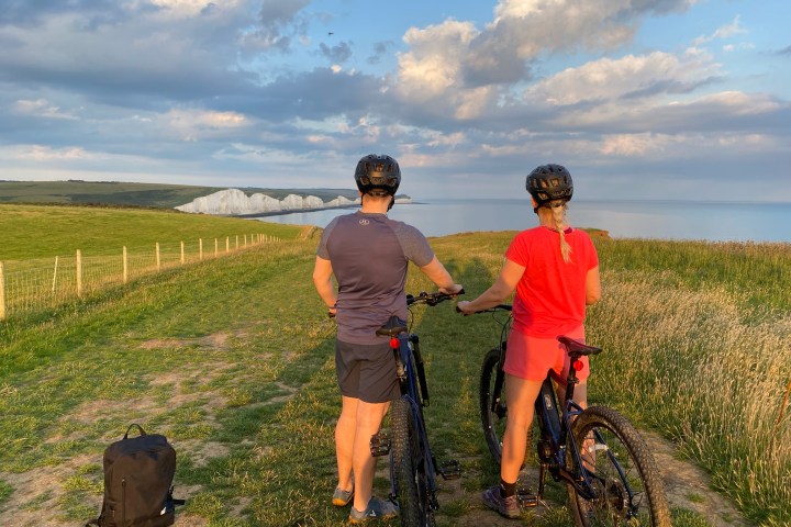 a man and a woman standing in a field with e-bikes