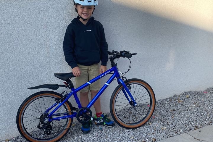 a little boy that is standing in front of a bicycle
