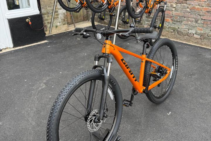 Orange bicycles parked outside on a stand.