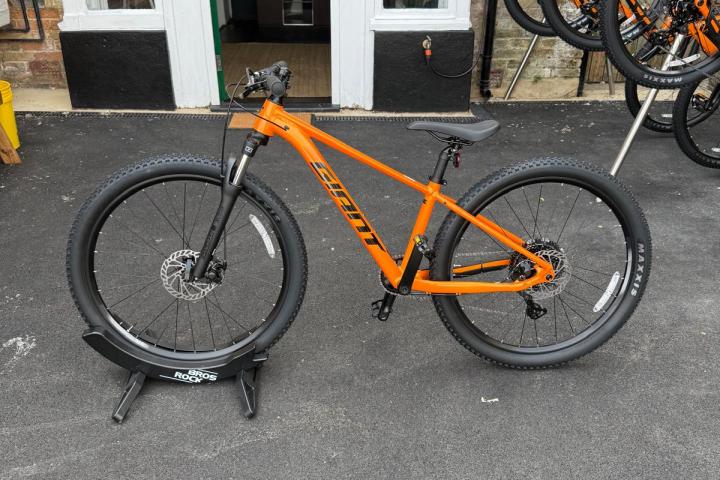 Orange mountain bike on display in front of a shop.