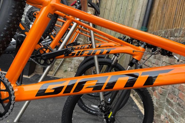 Row of orange bicycles with 'Giant' logo on black frames.