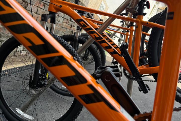 Orange mountain bikes parked in a row, close-up of frame with 'Giant' logo visible.