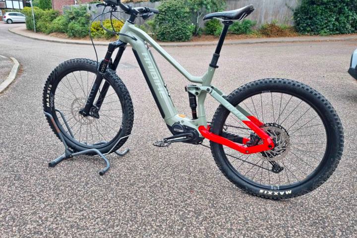 A gray and red mountain bike on a stand, parked on a street.