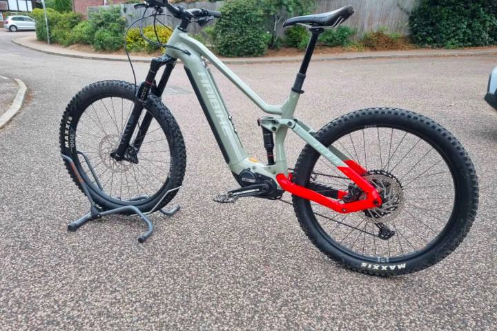 Mountain bike with green frame and red rear suspension on a stand.